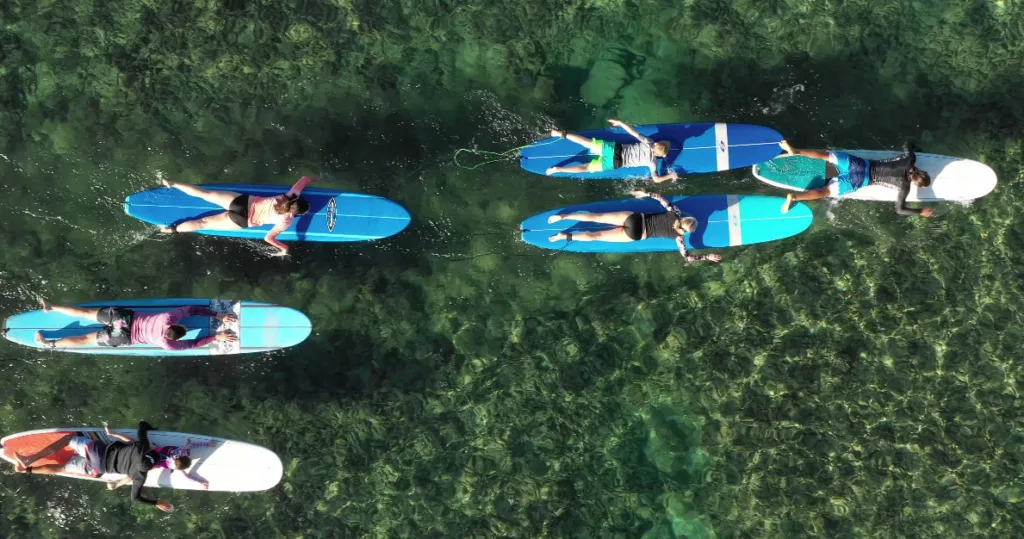 Group of beginners taking a surf lesson on sandy beach