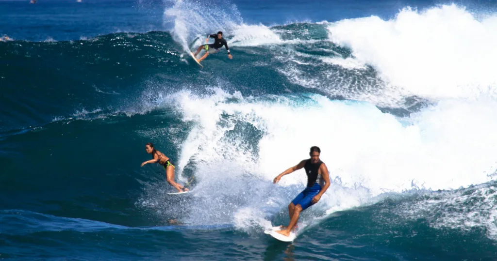 Surfers catching waves on the North Shore beach
