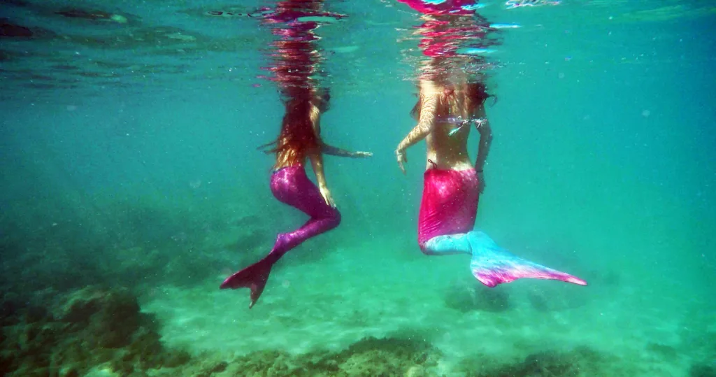 Person snorkeling with a mermaid tail underwater