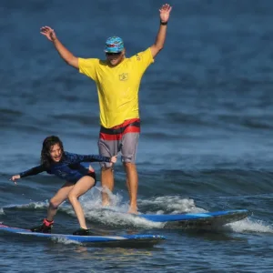 Instructor teaching individual how to surf on beach