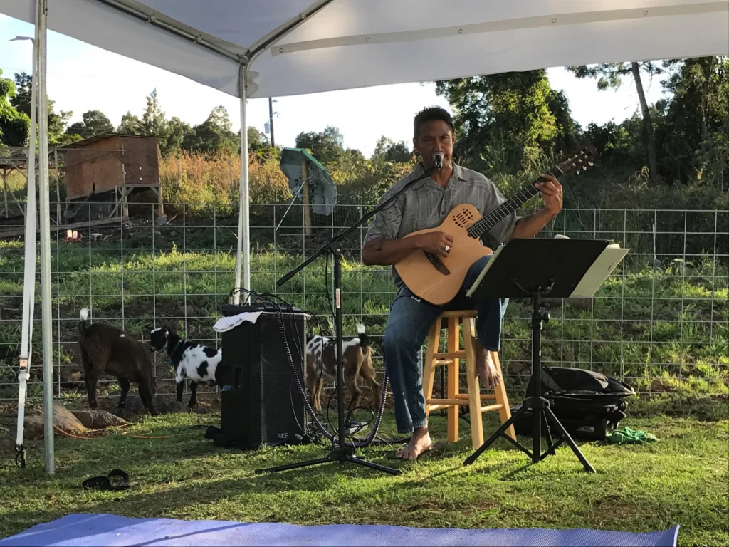 People practicing goat yoga during a Maui sunset with music