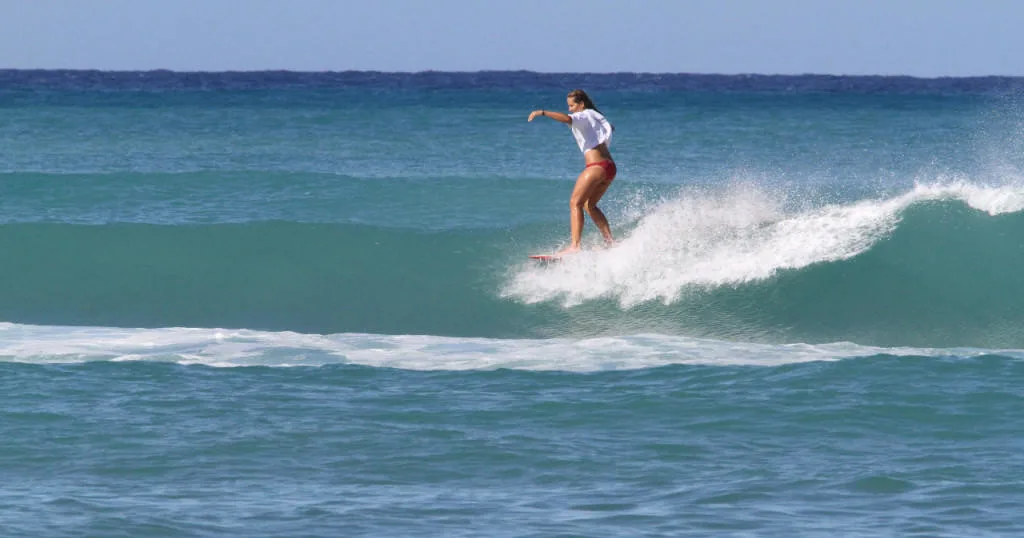 Surfers riding waves under bright sunny sky