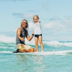 Instructor guiding two kids during private surf lesson
