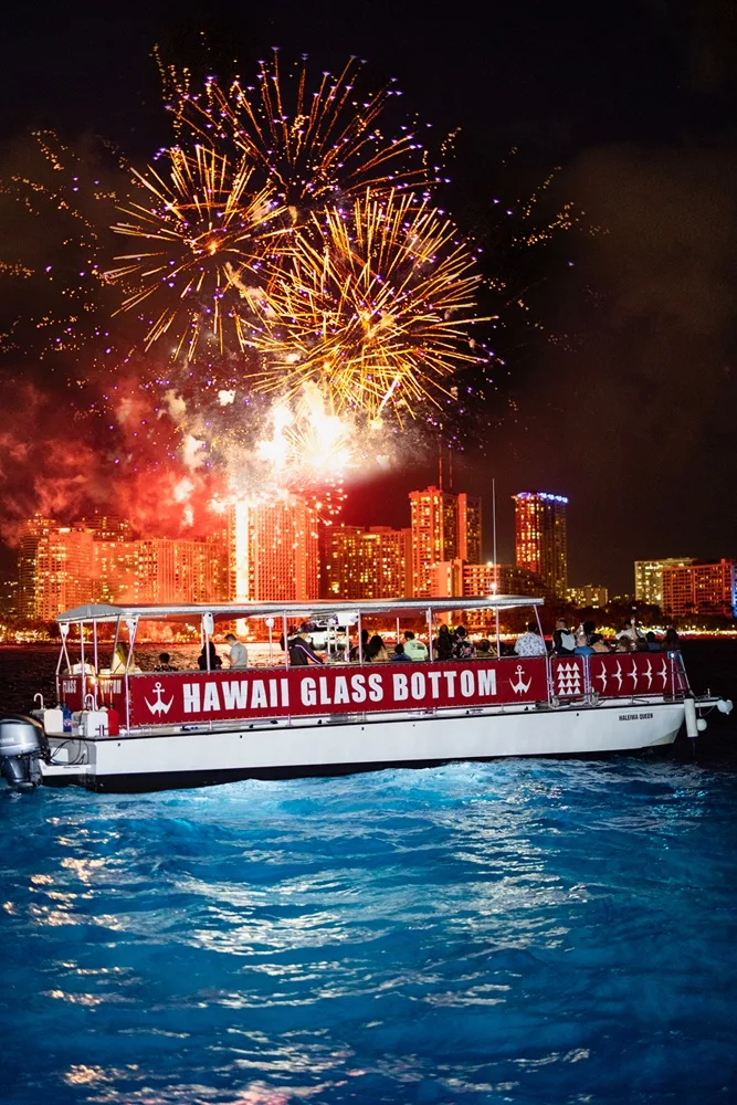 Boat cruising near Honolulu skyline at night