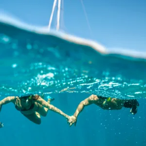 Sailboat gliding along Maui coastline with snorkelers aboard