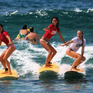 Group of beginner surfers learning on gentle waves