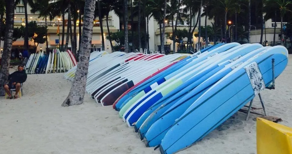 Stand-up paddleboards lined up on Waikiki beach sand