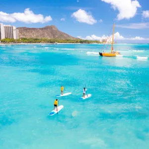 Three people taking a private paddleboarding lesson in Waikiki