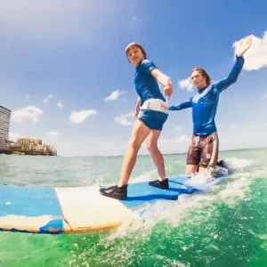 Young child learning to surf with instructor tandem style