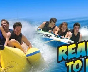 Group holding on tightly to banana boat in marina