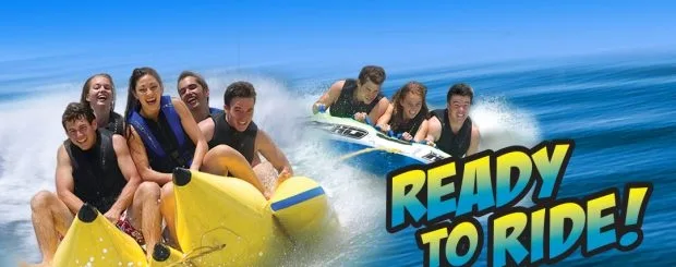 Group holding on tightly to banana boat in marina