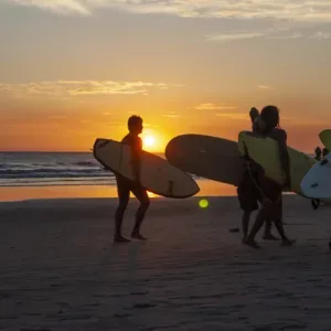 Surf instructor teaching beginner on sandy beach