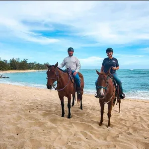 Couple horseback riding on private oceanfront trail
