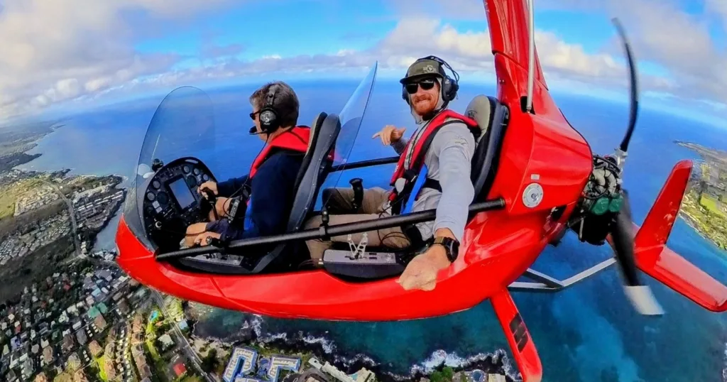 Gyroplane flying over Kona coastline with instructor