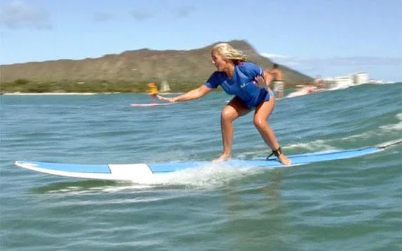 Surf instructor helping student catch wave