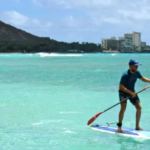 Instructor teaching standup paddleboarding on calm water