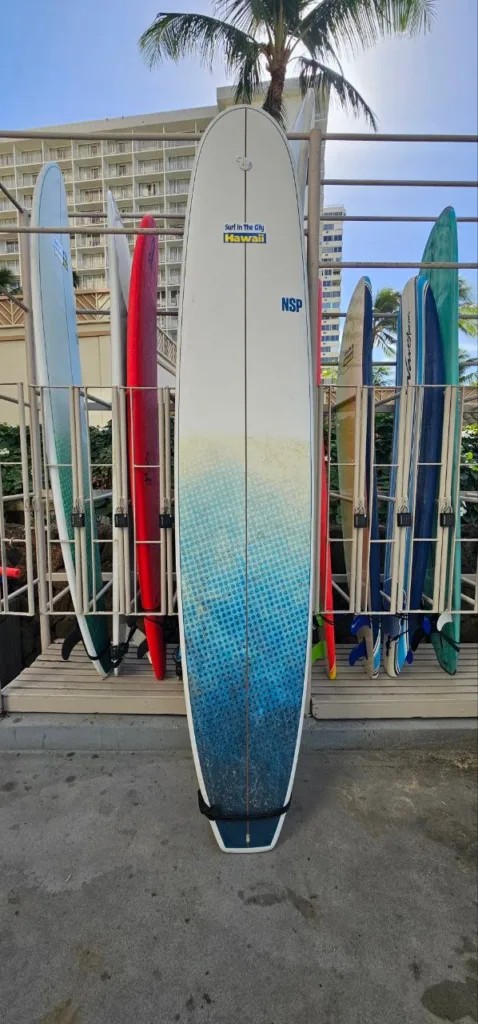 Long 11-foot epoxy surfboard resting near locker