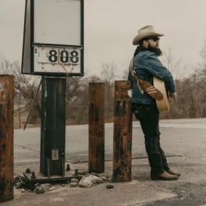 Musician playing guitar on stage with microphone
