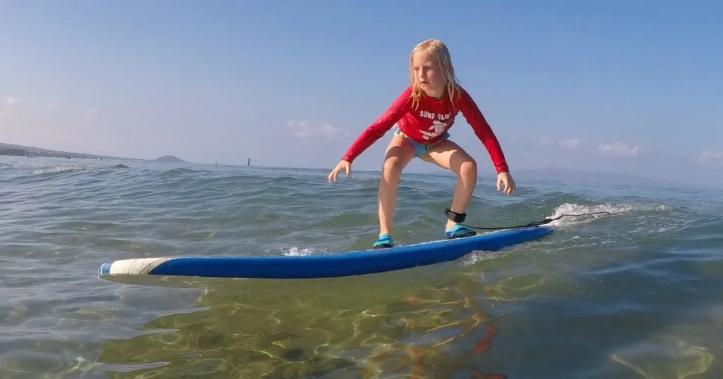 Children learning to surf in shallow water