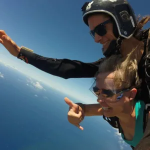 Skydiver in tandem harness freefalling over landscape