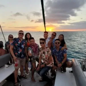 Catamaran sailing near Waikiki coastline at sunset