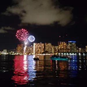 Boat cruising Waikiki with fireworks lighting the sky