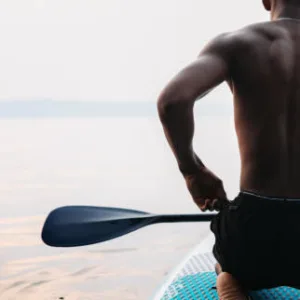 Instructor guiding student on stand-up paddleboard lesson