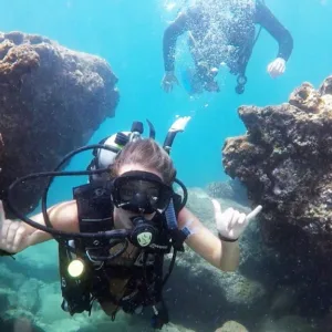 Person learning scuba diving in clear ocean water