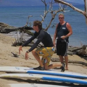 Two paddleboarders receiving instruction from guide in ocean