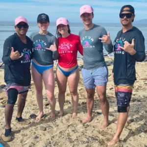 Group of three surfers getting land lesson on beach