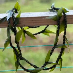 Hands crafting fresh flower lei on table
