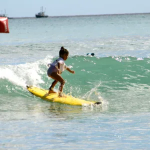 Young child learning to surf with private instructor