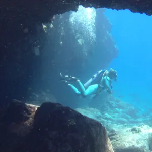Instructor guiding scuba divers near coral reef