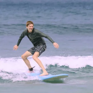 Hawaiian surf instructor helping student catch a wave