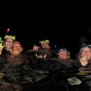 Group snorkeling with manta rays under night sky