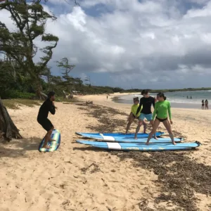 Surf instructor coaching private group on beach