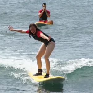 Instructor guiding two students during a surfing lesson