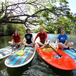 Beginners receiving group instruction during first stand-up paddleboard lesson