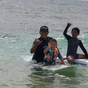 Child learning to surf with instructor support