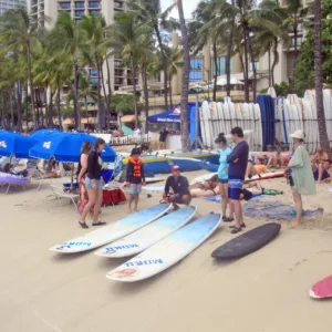 Group lesson with instructor teaching beginners to surf