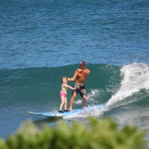Individual practicing surfing on gentle island waves near shore
