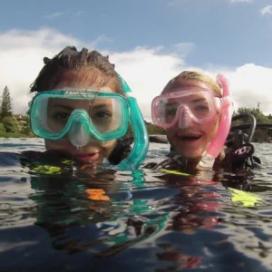 Divers exploring coral reefs at Tunnels shore dive
