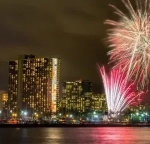 Sailboat silhouetted against vibrant Friday night fireworks
