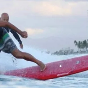 Surfer receiving advanced longboard lesson from champion instructor