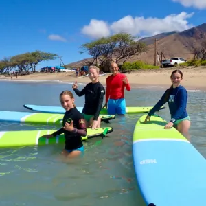 Family learning to surf together on gentle beach waves