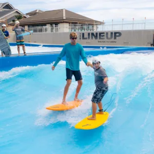 Surf instructor teaching beginner on gentle ocean waves