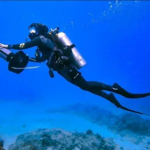 Scuba diver using propulsion vehicle under clear ocean water