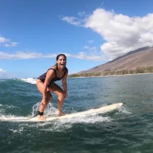 Surf instructor assisting student on gentle ocean waves