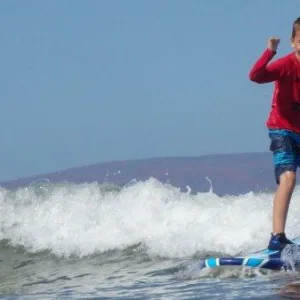 Children catching waves during beginner surf class