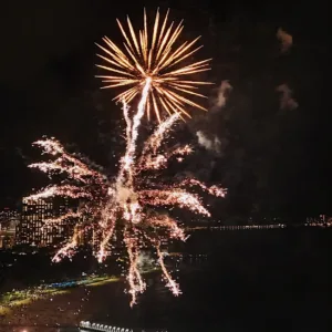 Sailboat cruising under colorful fireworks at sunset
